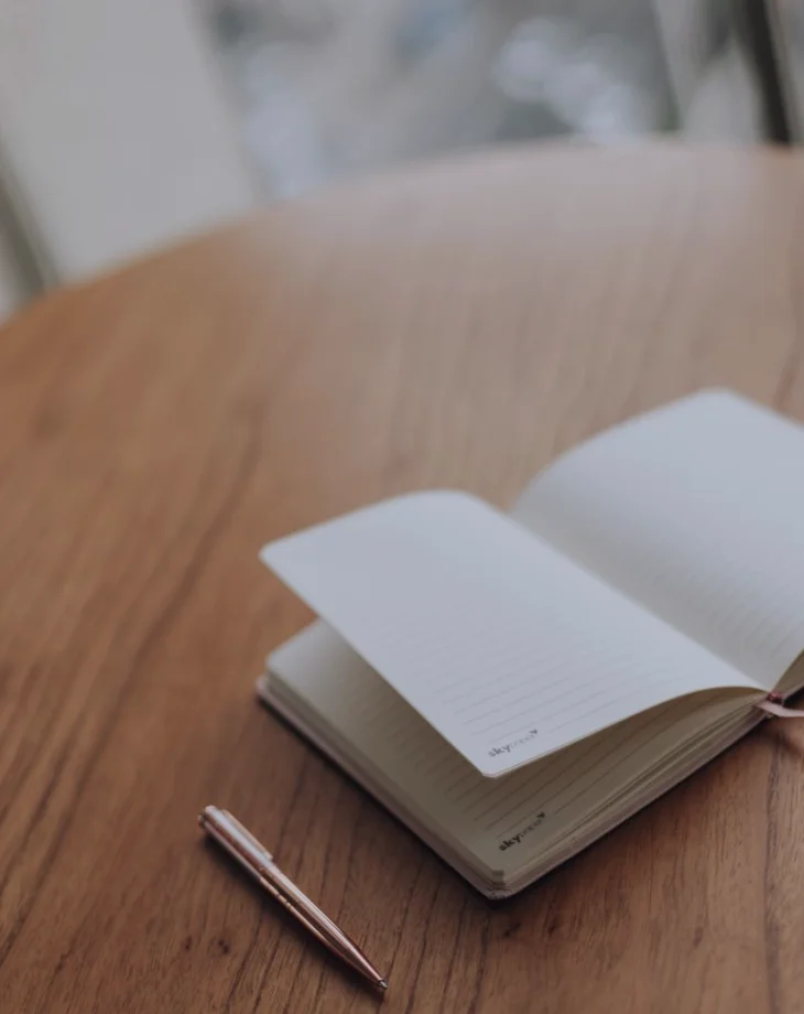 Notesbog, optager og udkast liggende klar på et skrivebord